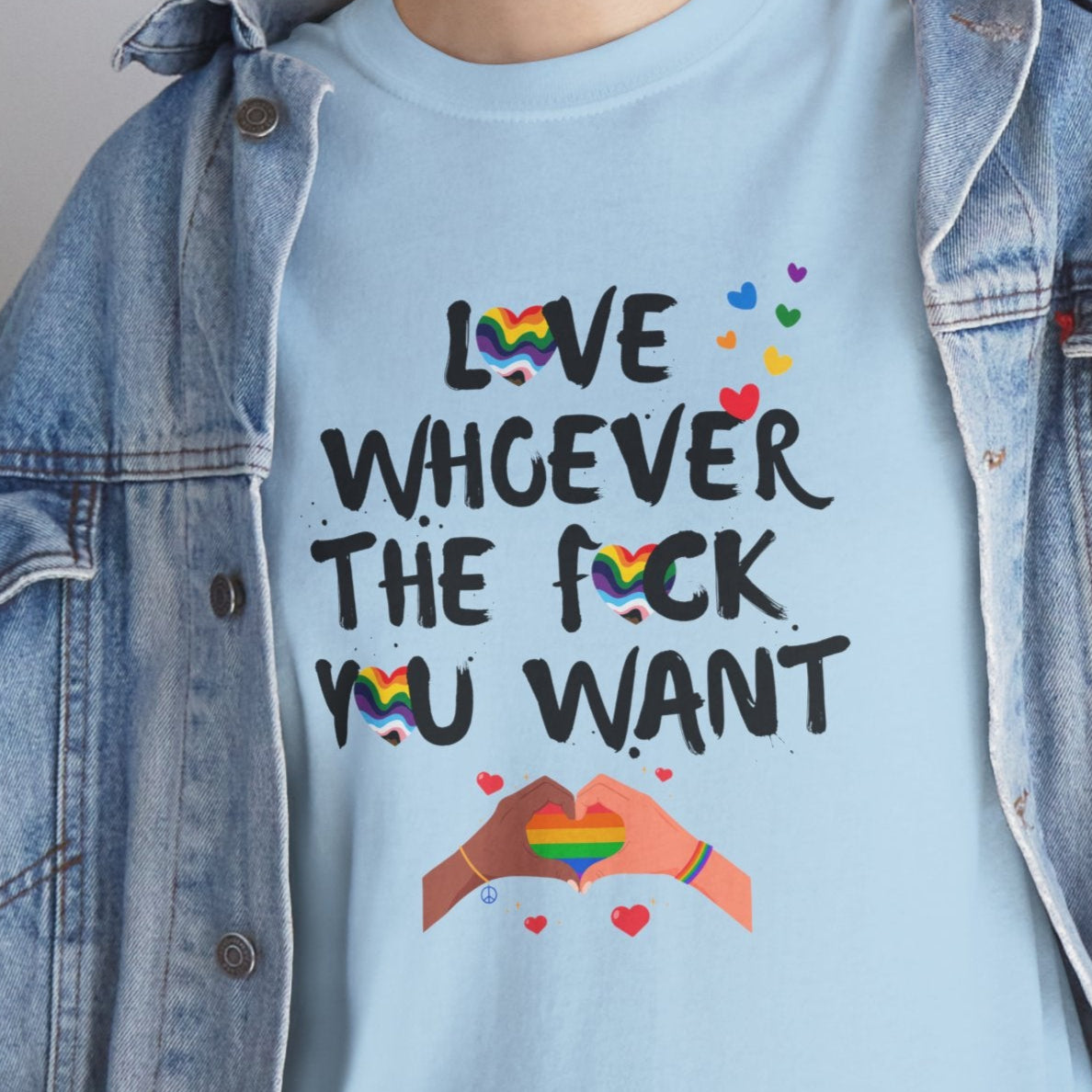 Person wearing a light blue t-shirt with a colorful graphic and text, paired with a denim jacket.